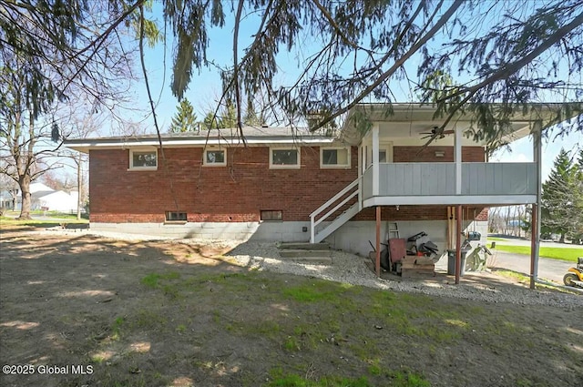 rear view of house featuring crawl space, a ceiling fan, a garage, brick siding, and stairs