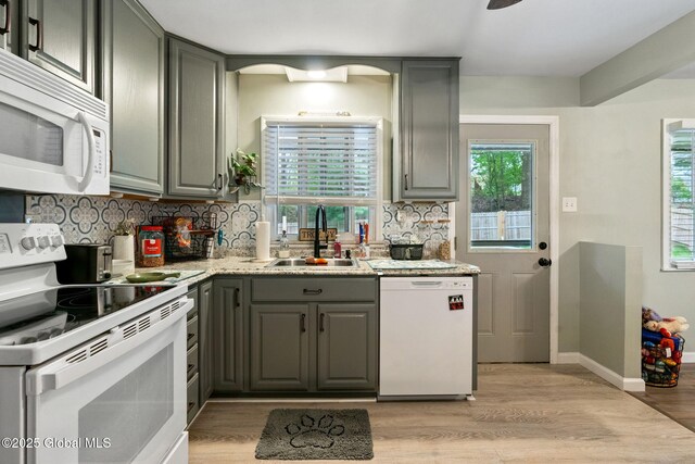 kitchen with white appliances, a sink, gray cabinetry, and light wood-type flooring