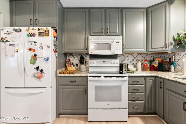 kitchen featuring white appliances, gray cabinetry, decorative backsplash, and light wood-style floors