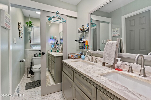 full bath with toilet, vanity, tile patterned floors, a wainscoted wall, and tile walls