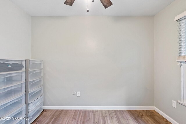 empty room with ceiling fan, wood finished floors, and baseboards
