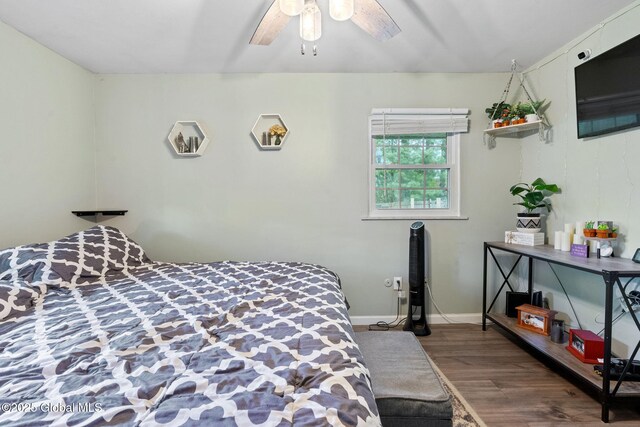bedroom featuring wood finished floors, a ceiling fan, and baseboards