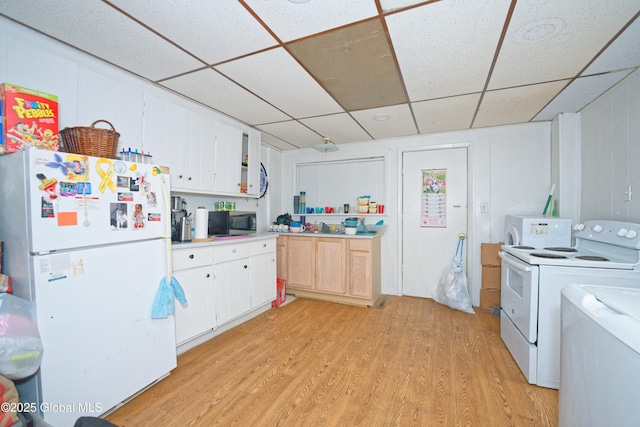 kitchen with light wood finished floors, freestanding refrigerator, a paneled ceiling, stainless steel microwave, and light countertops