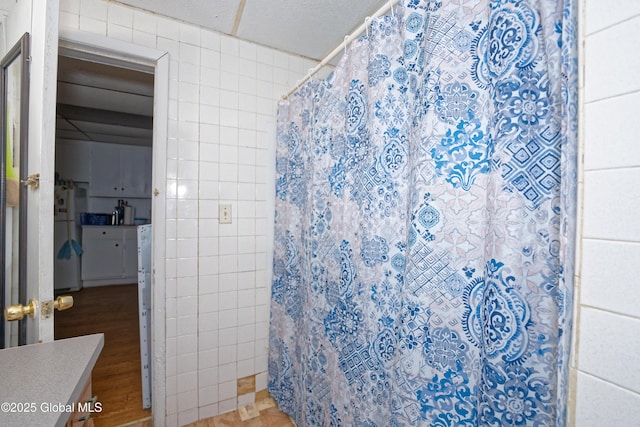 full bathroom with tile walls, a shower with shower curtain, and wood finished floors
