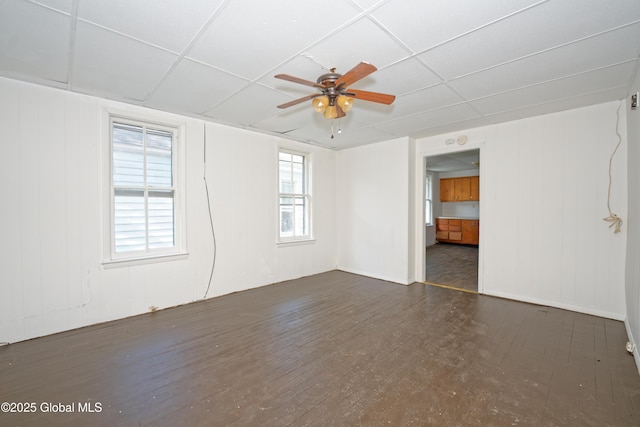 unfurnished room featuring a drop ceiling, wood finished floors, and a ceiling fan