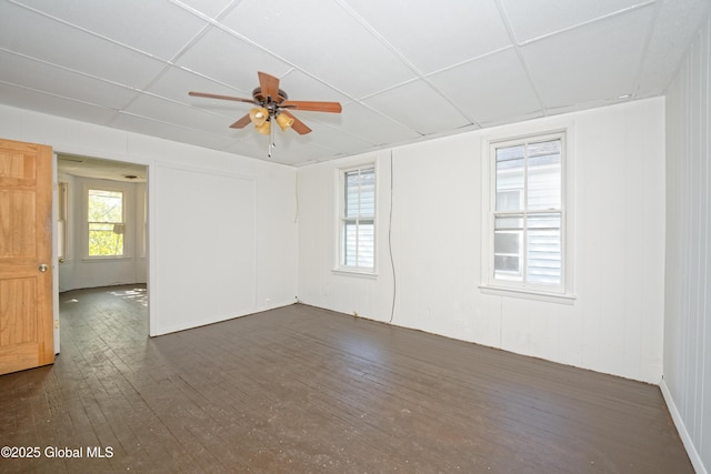empty room featuring a paneled ceiling, ceiling fan, and dark wood-style floors