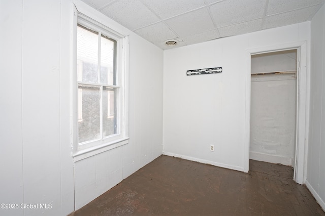 unfurnished bedroom with a drop ceiling, a closet, and visible vents