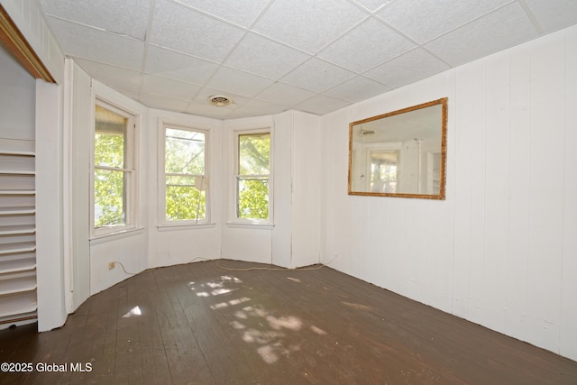 spare room featuring hardwood / wood-style floors, plenty of natural light, and a drop ceiling