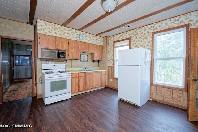 kitchen with a sink, visible vents, dark wood-type flooring, white appliances, and light countertops
