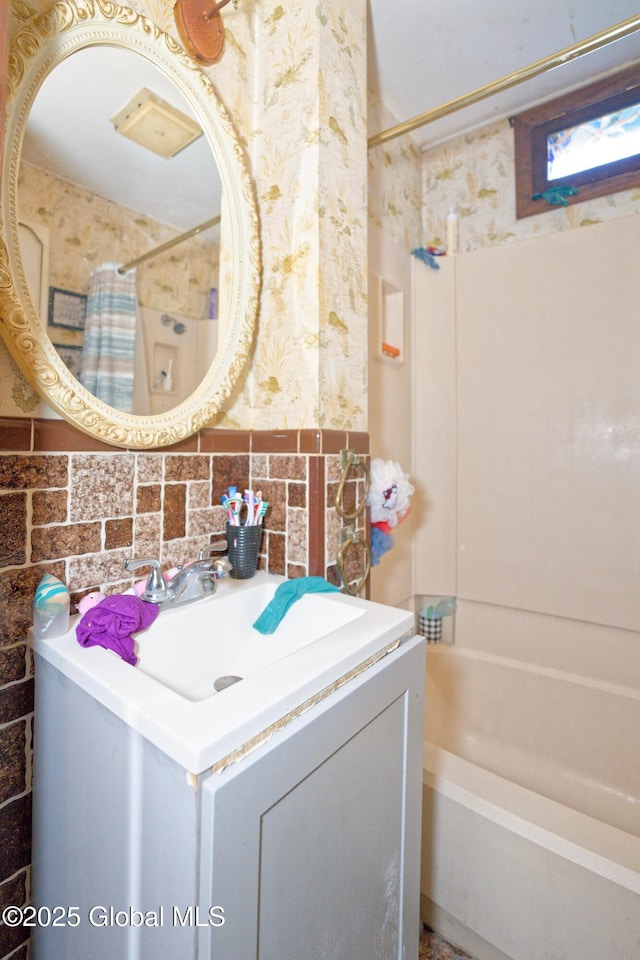 bathroom featuring vanity, tile walls, and shower / bath combo with shower curtain