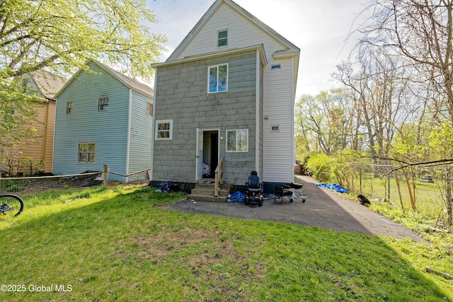 rear view of house featuring a lawn, entry steps, and fence