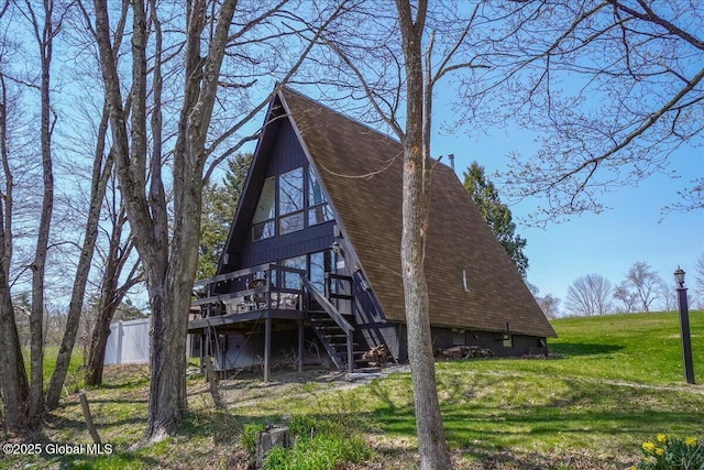 back of property featuring stairway, roof with shingles, a wooden deck, and a lawn