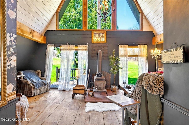sunroom / solarium featuring a wood stove, a wealth of natural light, and an inviting chandelier