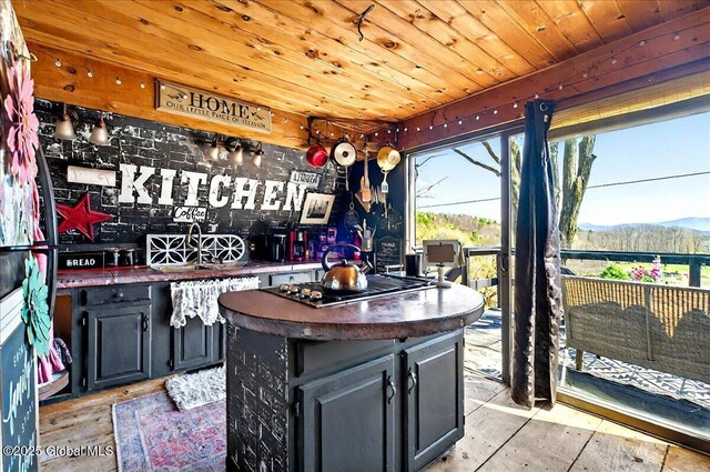 bar featuring wooden ceiling, stainless steel gas cooktop, bar, a mountain view, and light wood finished floors