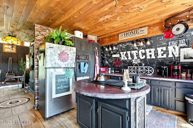 kitchen with stovetop, wooden ceiling, oven, a kitchen island, and freestanding refrigerator