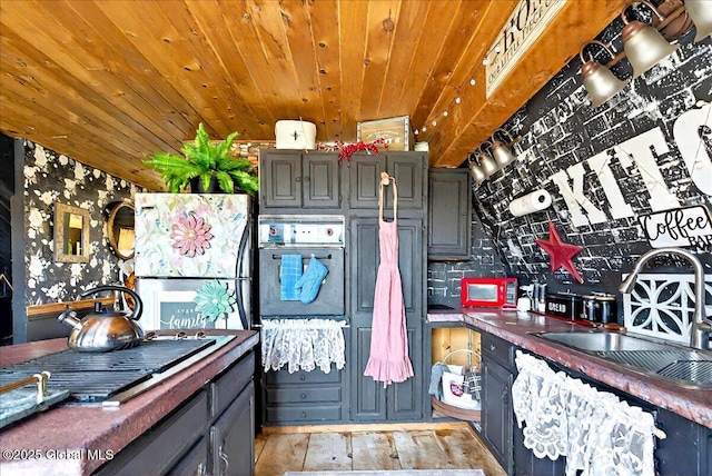 kitchen with gray cabinetry, wood ceiling, wall oven, and a sink