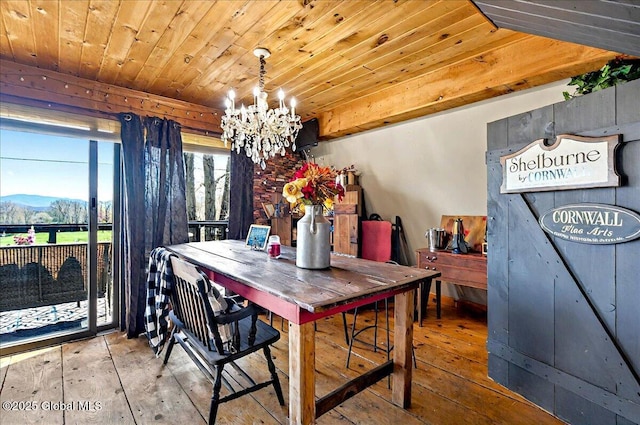 dining space featuring hardwood / wood-style floors, a notable chandelier, a mountain view, and wood ceiling