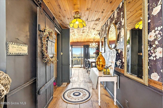 hall with wooden ceiling, hardwood / wood-style floors, a barn door, and a chandelier