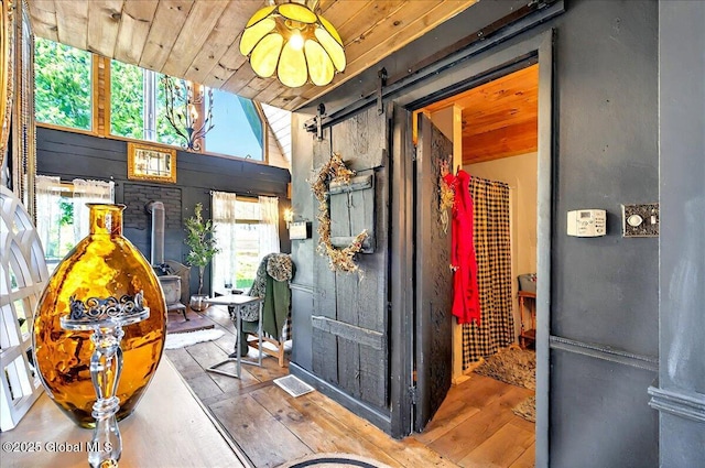 interior space with wood finished floors, a barn door, and wood ceiling