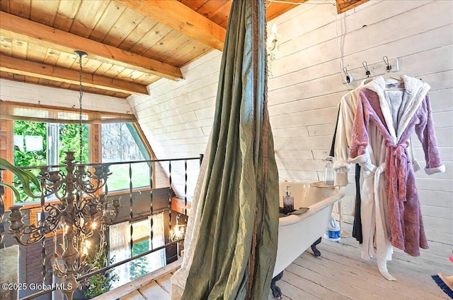 interior space featuring beamed ceiling, a notable chandelier, wooden walls, wood ceiling, and wood finished floors