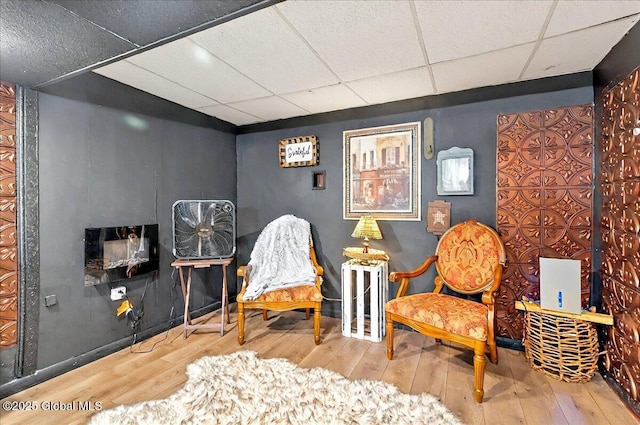 sitting room with a paneled ceiling and hardwood / wood-style floors