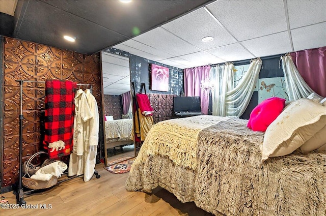 bedroom with wood-type flooring and a drop ceiling