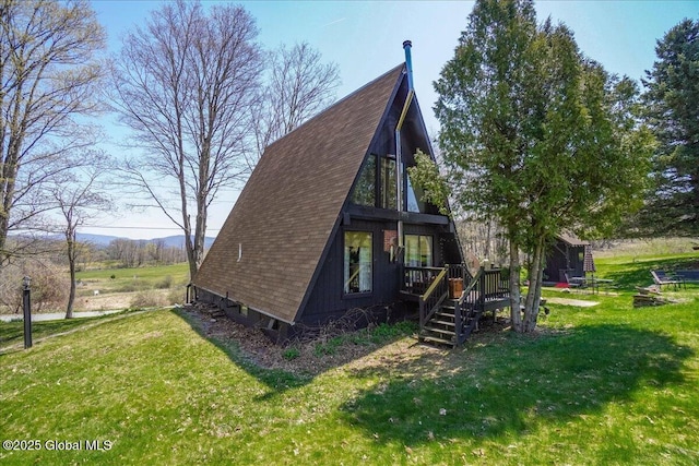 exterior space with a deck, a yard, a shingled roof, and stairway