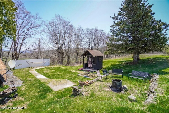view of yard featuring an outbuilding, a shed, fence, and an outdoor fire pit