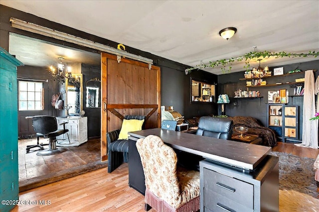 home office featuring a barn door, an inviting chandelier, and wood finished floors