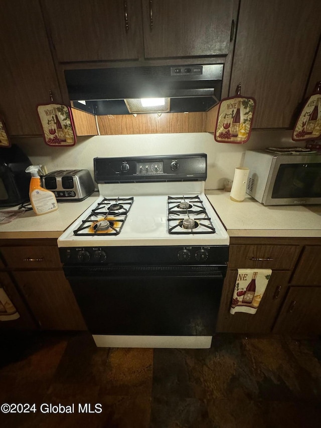 kitchen featuring dark brown cabinets, gas range, light countertops, stainless steel microwave, and under cabinet range hood