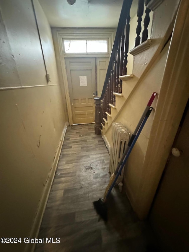 doorway to outside featuring radiator, wood finished floors, and stairs