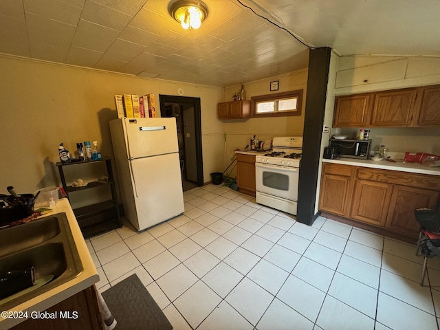 kitchen with brown cabinetry, a sink, white appliances, and light countertops