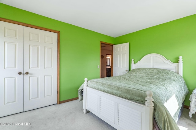 bedroom with baseboards, a closet, and light colored carpet