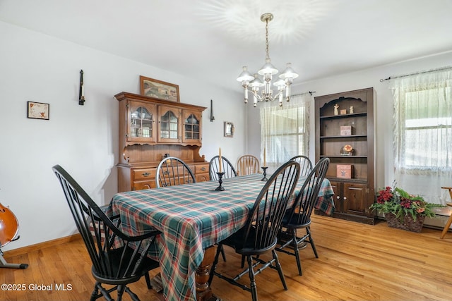 dining area featuring baseboards, a notable chandelier, and light wood-style floors
