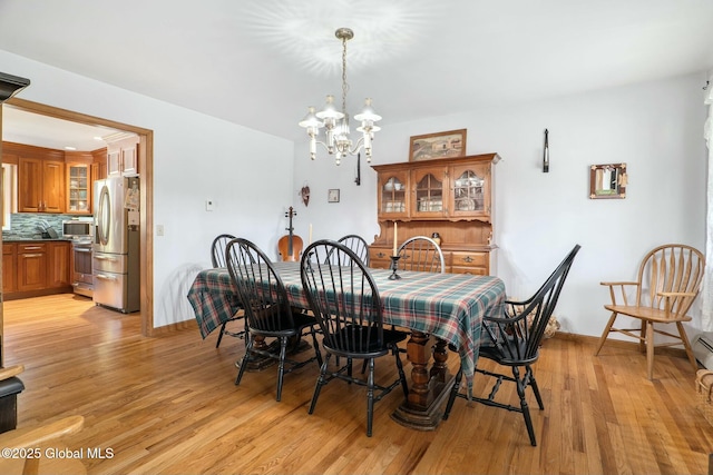 dining space with a chandelier, light wood-style floors, and baseboards