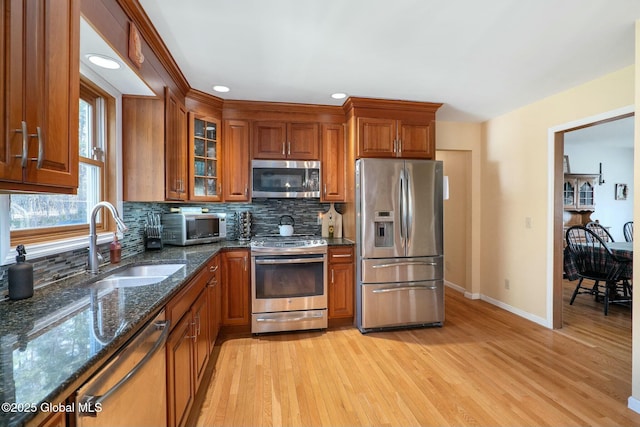 kitchen featuring brown cabinets, appliances with stainless steel finishes, decorative backsplash, and a sink