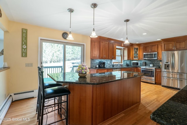 kitchen featuring light wood-style flooring, a sink, tasteful backsplash, brown cabinets, and appliances with stainless steel finishes