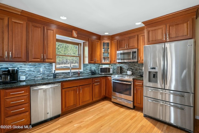 kitchen featuring brown cabinetry, appliances with stainless steel finishes, a sink, and light wood-style flooring