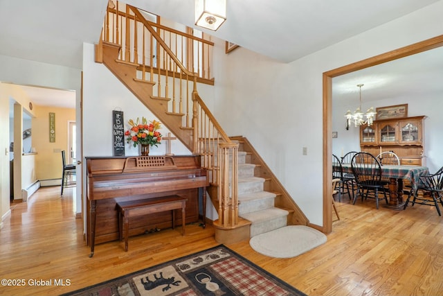 staircase featuring baseboards, wood finished floors, and a chandelier