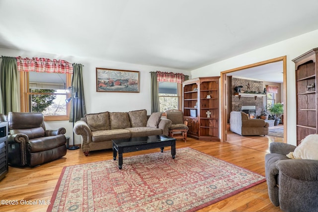 living area with light wood-type flooring, plenty of natural light, and a fireplace