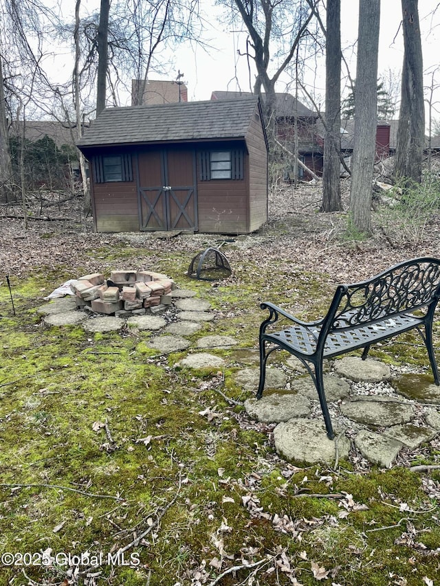 view of yard with a fire pit, a storage unit, and an outbuilding