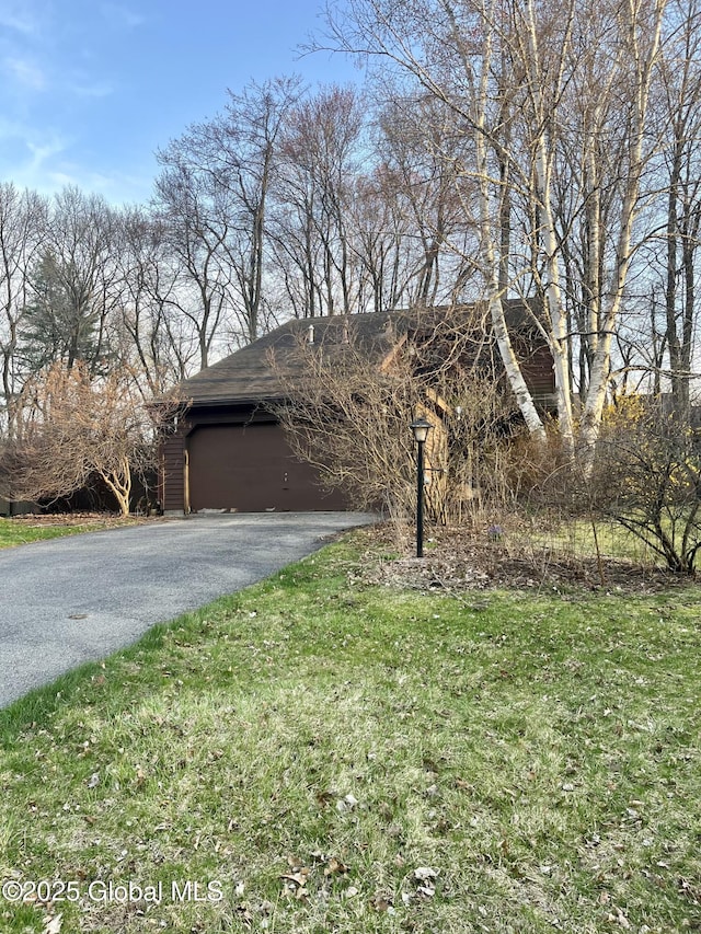 view of front facade featuring asphalt driveway, a garage, and a front lawn