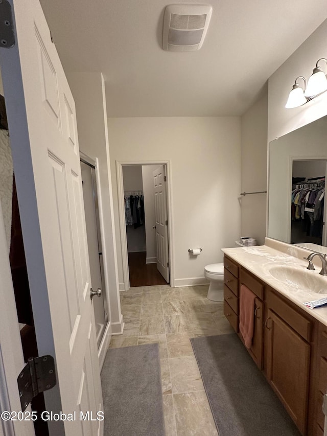 full bath featuring a shower stall, vanity, toilet, visible vents, and baseboards