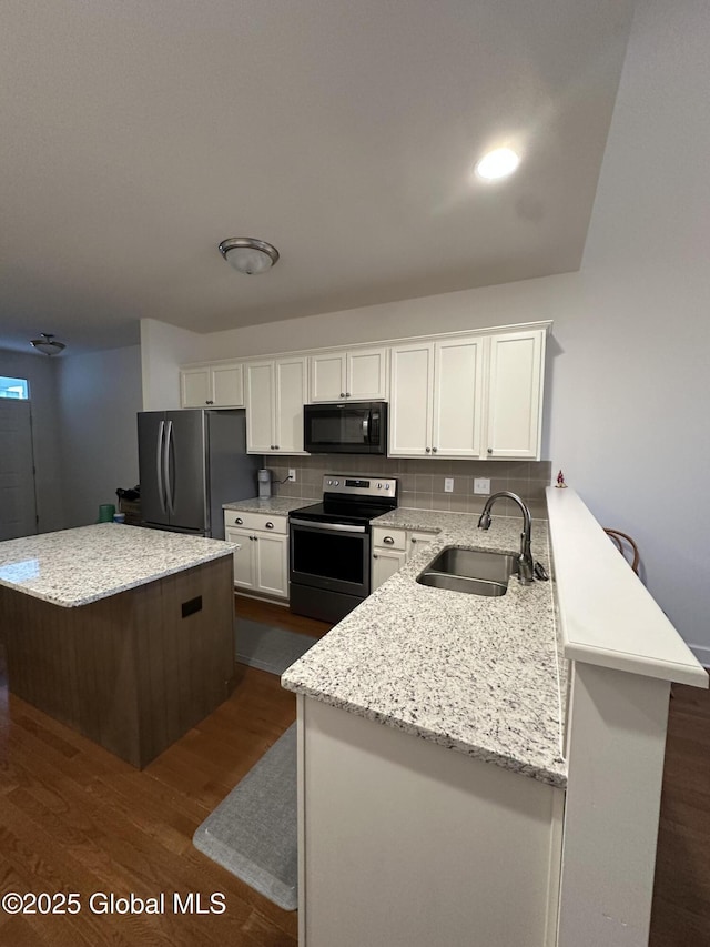 kitchen with a sink, dark wood-style flooring, a center island, white cabinets, and appliances with stainless steel finishes