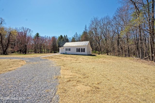 manufactured / mobile home featuring a view of trees, a front yard, and metal roof