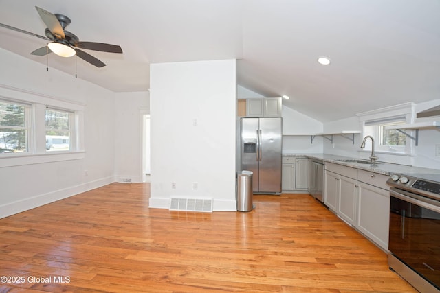 kitchen with stainless steel appliances, a sink, visible vents, a ceiling fan, and light stone counters