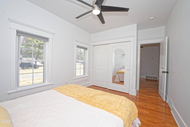 bedroom with a closet, wood finished floors, visible vents, and a ceiling fan