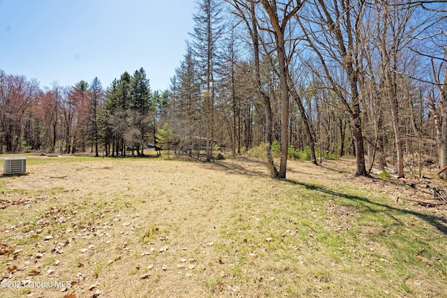 view of yard with a wooded view and central AC unit