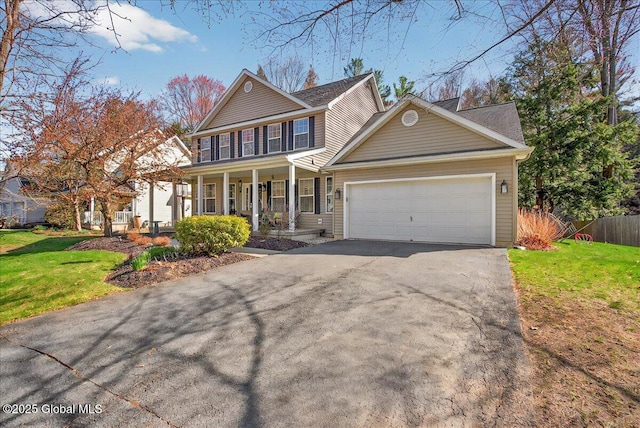 view of front of home featuring covered porch, an attached garage, driveway, and a front lawn