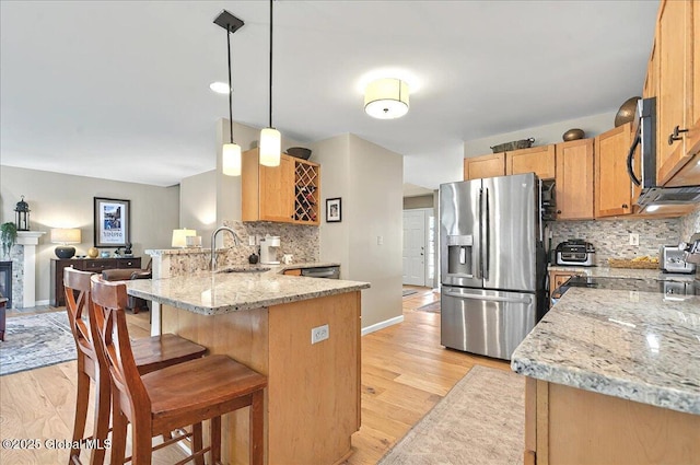 kitchen with a sink, light wood-style flooring, a peninsula, tasteful backsplash, and stainless steel refrigerator with ice dispenser